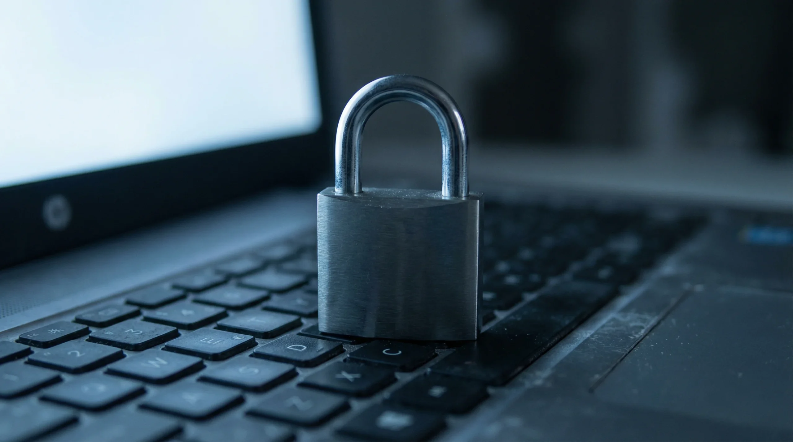 Padlock resting on a laptop keyboard with soft blue light